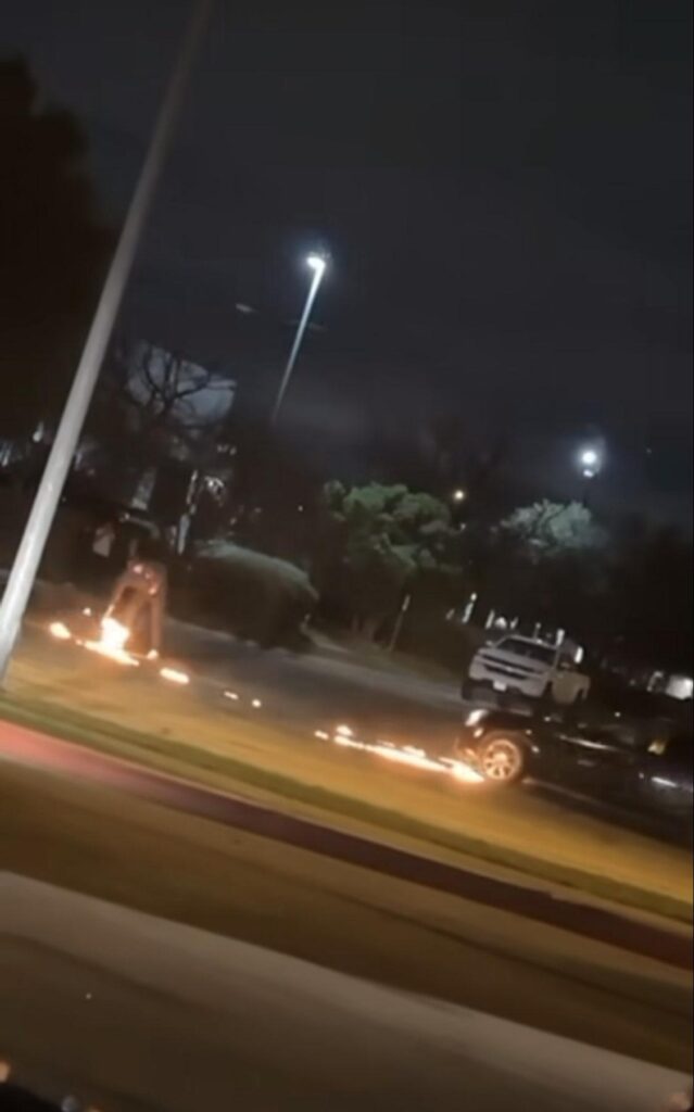 A car doing donuts in a cul de sac leaves a trail of fire behind it